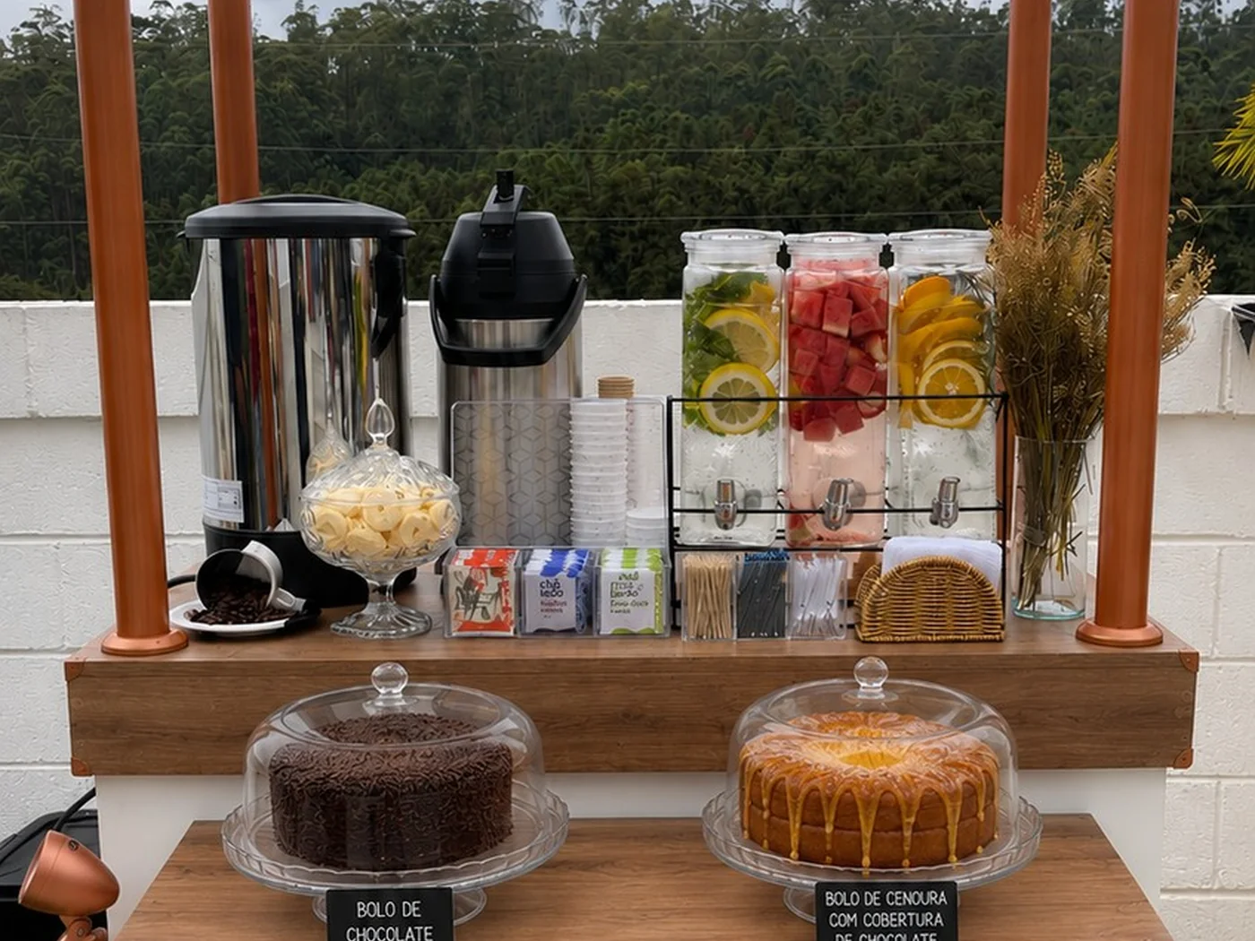Carrinho gourmet montado como estação de coffee break com café, bolos e utensílios